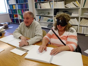 Tom and Vicki reading side-by-side at the table in the library