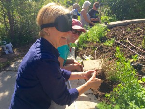 Woman wearing sleepshades reaching a small plant over its hole