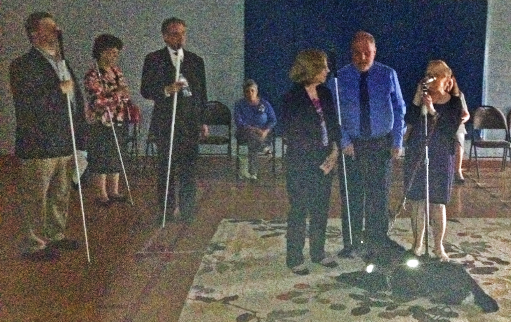 Three people stand at the front of a dimly-lit gym