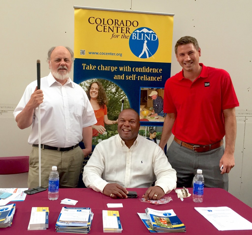 Man seated before the CCB banner, flanked by two other men