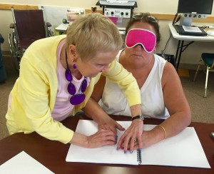 Two women arranging their hands on a page of Braille