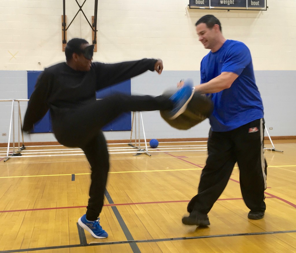 Student makes a High kick into a pad held by his instructor