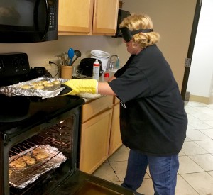 woman in sleep shades removes large sheet of cookies from a glowing oven