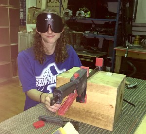 a young woman under sleep shades screws on the hinges to a keepsake box held by clamps