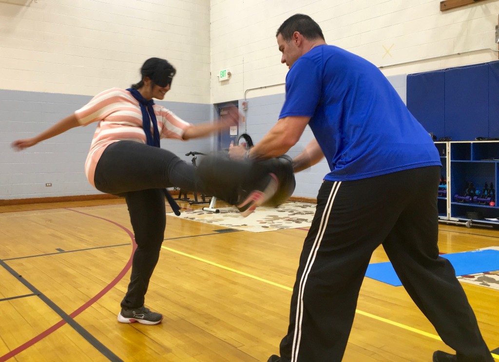 Woman takes her kick at the pad held by her instructor