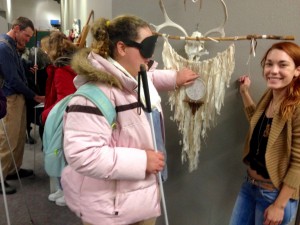 a young woman examines a feathery artwork hung on the wall