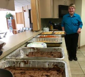 large pans are lined up on the counter below the serving window, the chef standing at the far end