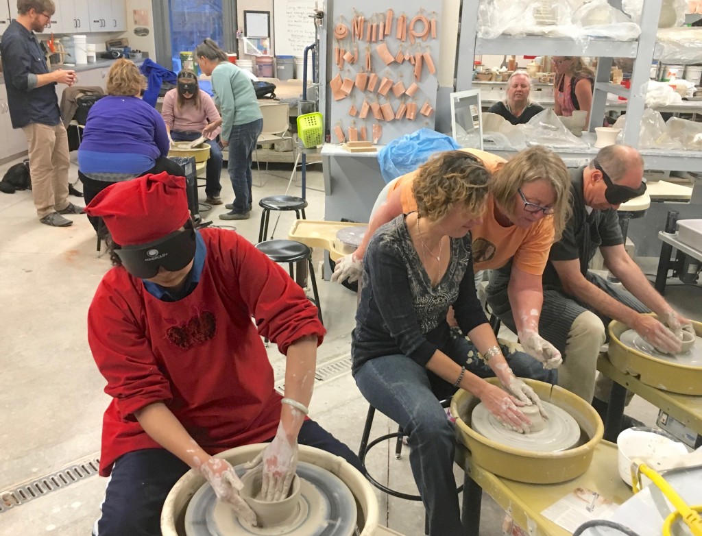 Six people work their clay on pottery wheels