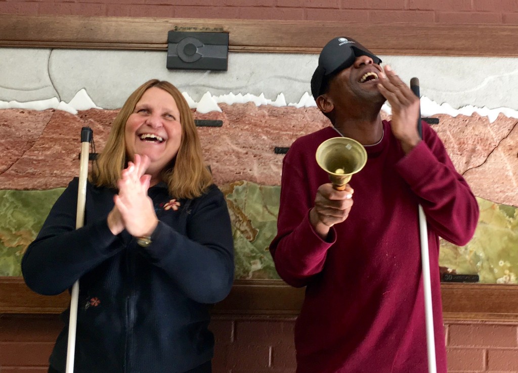 A man rings his bell with a wide grin while a woman applauds