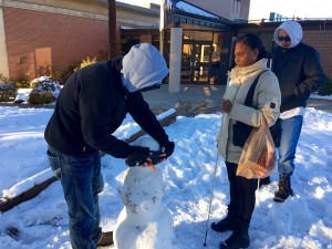 Two men and a womanadd sleepshades and white cane to their snow person that has a carrot nose.