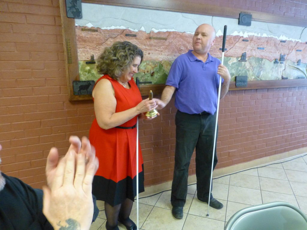 A man hands a woman a hand bell