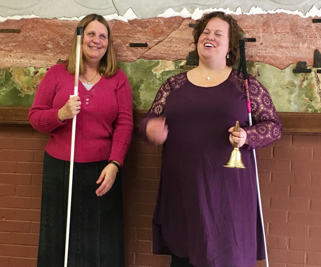 two joyful women stand together, one ringing her Freedom Bell