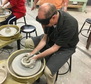 Peter forms a bowl on the potters wheel with both hands cupped around the clay and both thumbs forming the center