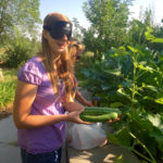 Tabea showing two cucumbers she just picked from the garden