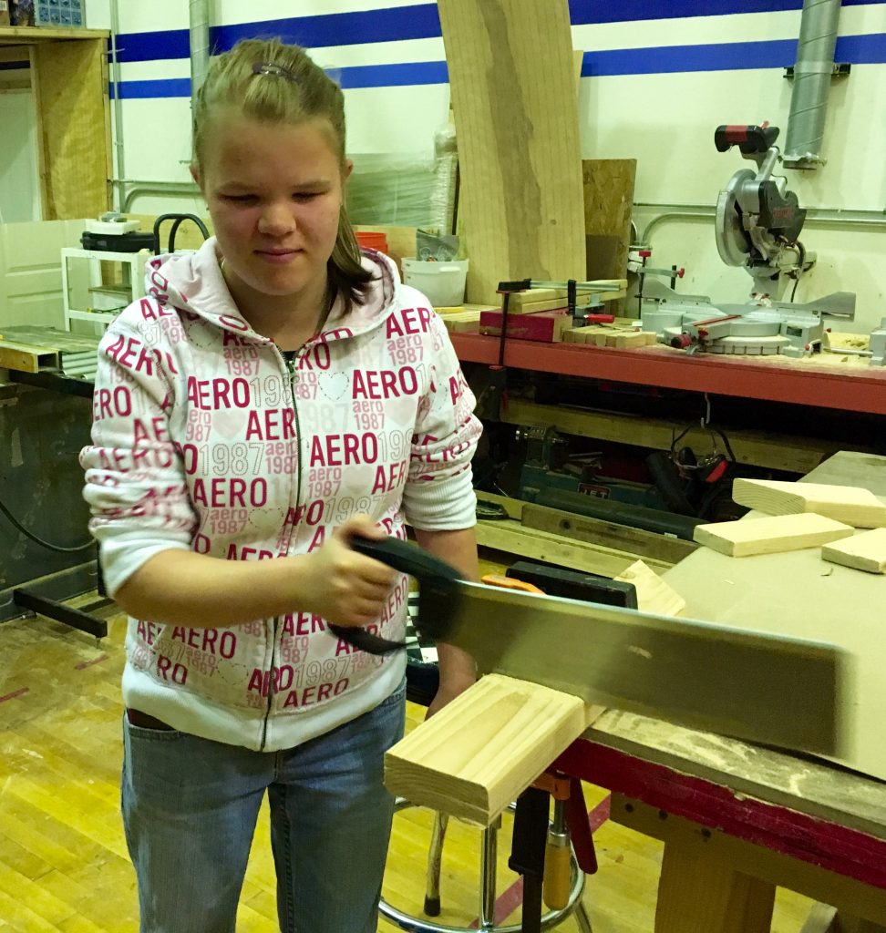 Vika using a hand saw in the woodshop