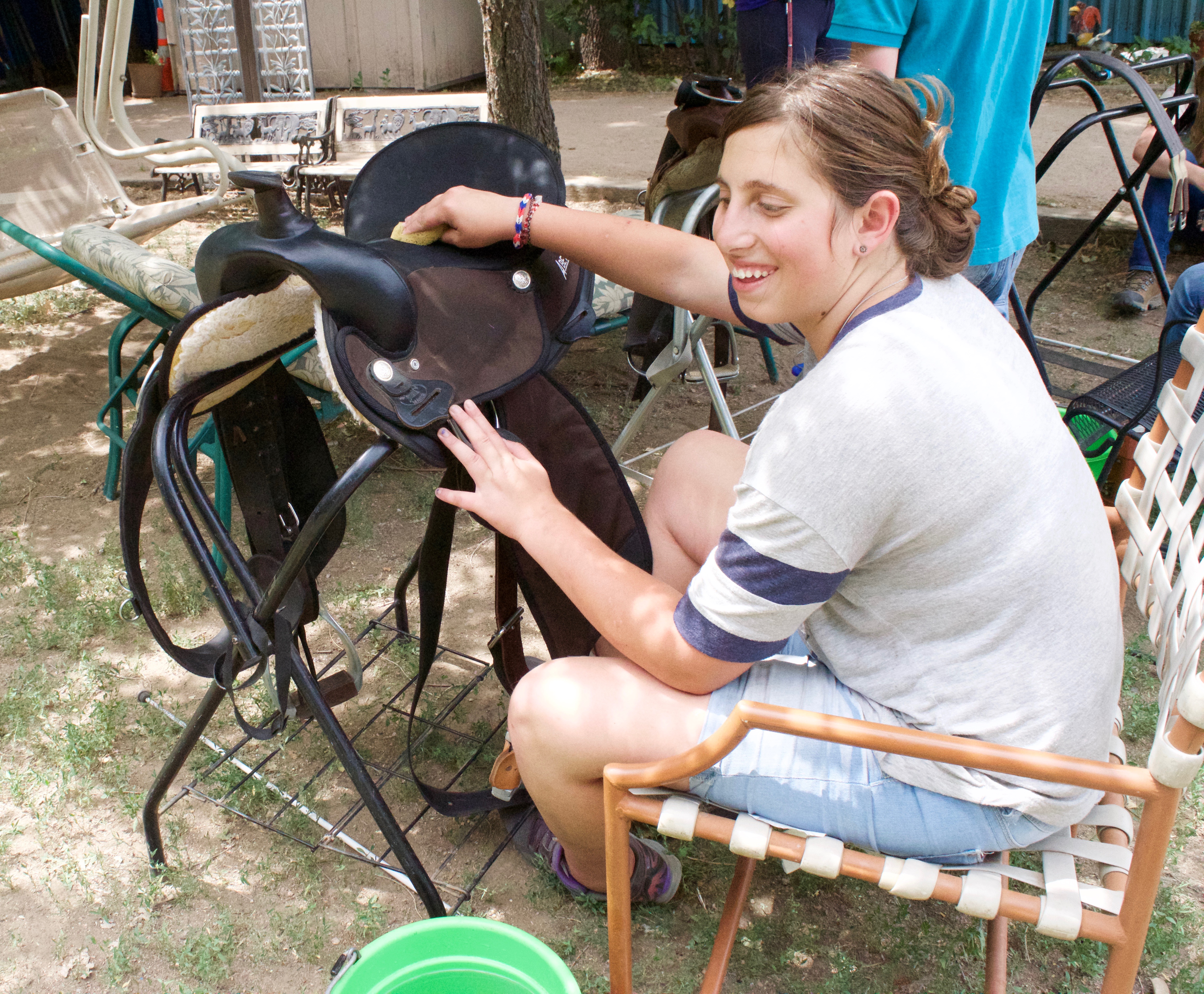 Christina works on cleaning and polishing a saddle