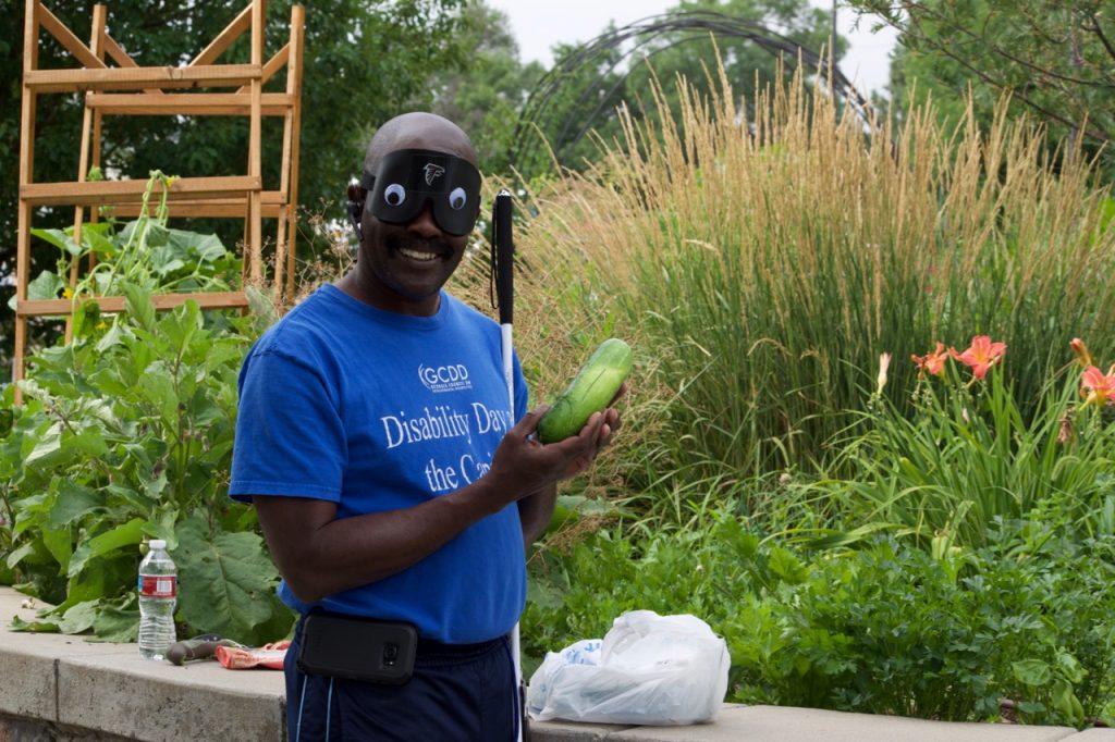 a smiling man shows a freshly picked cucumber