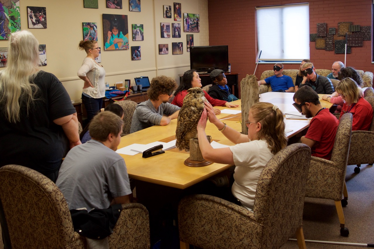 Group shot - The class listens to bird sounds while CG looks at a mount of a Great Horned Owl