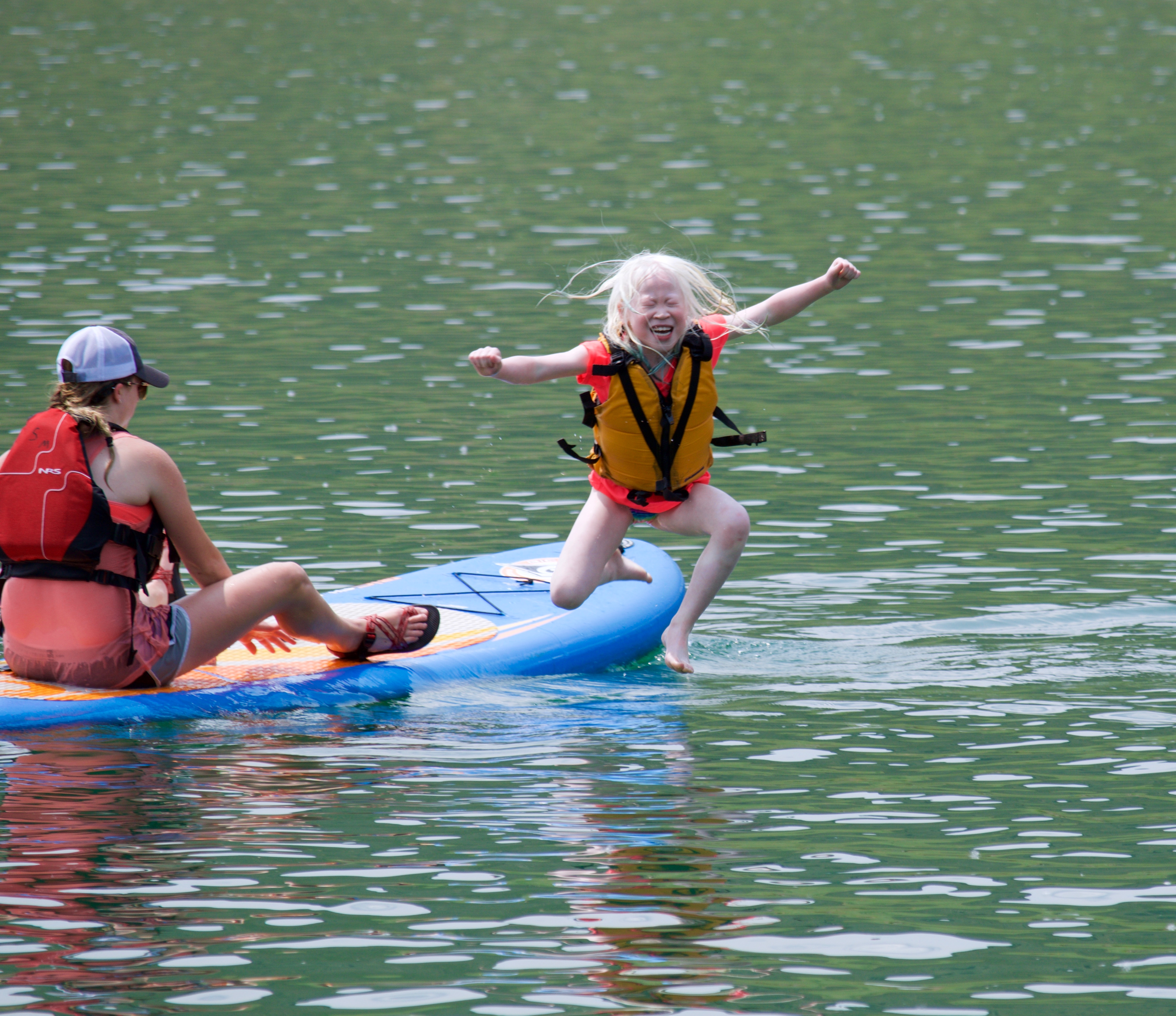 Cloe leaping from a paddle board during Confidence Camp