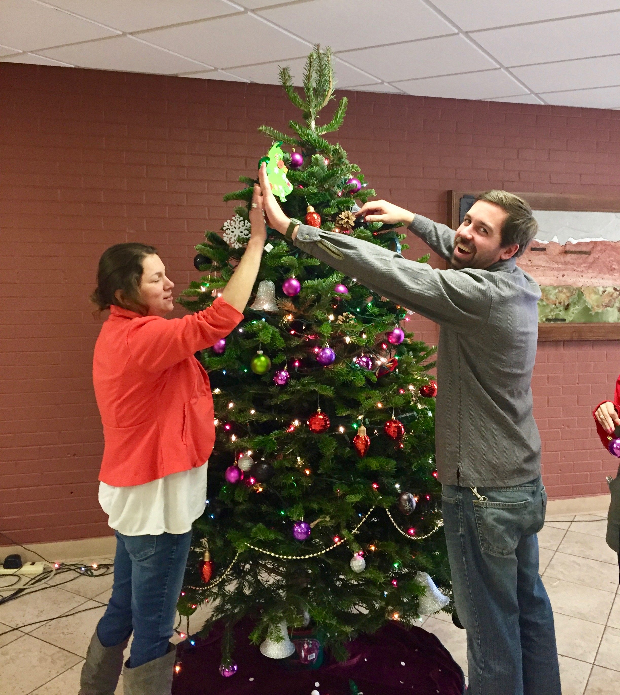 Shop Instructor Chris and Home Management Instructor Delfina high fiving in front of the tree