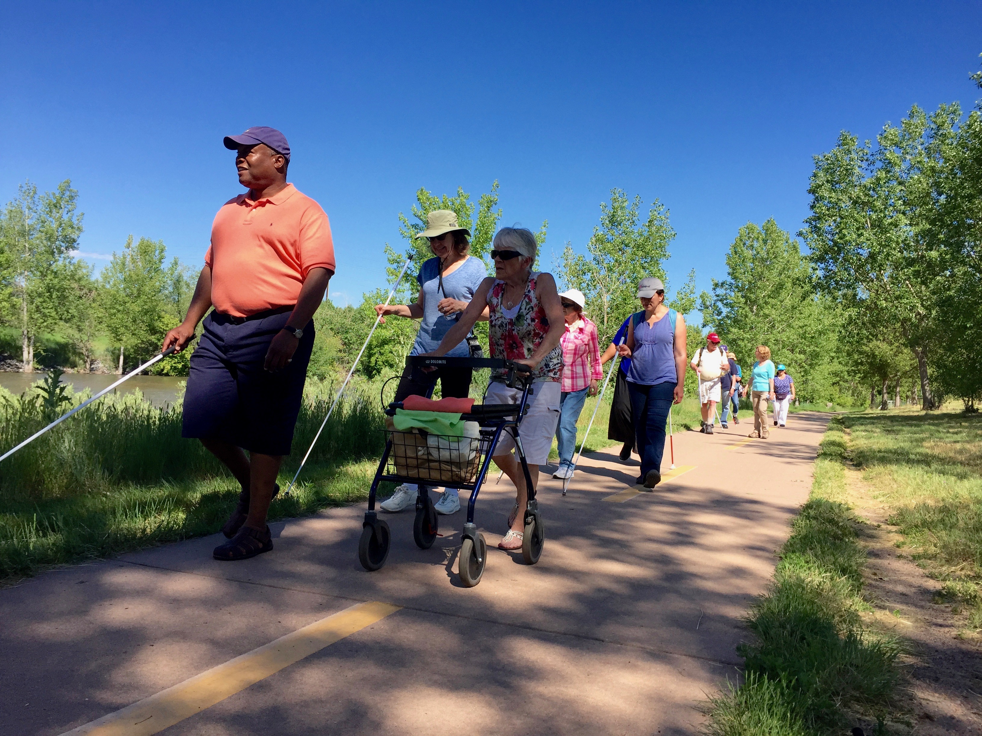 Wayne leads a hike along a river trail with a group of 9 CCB seniors