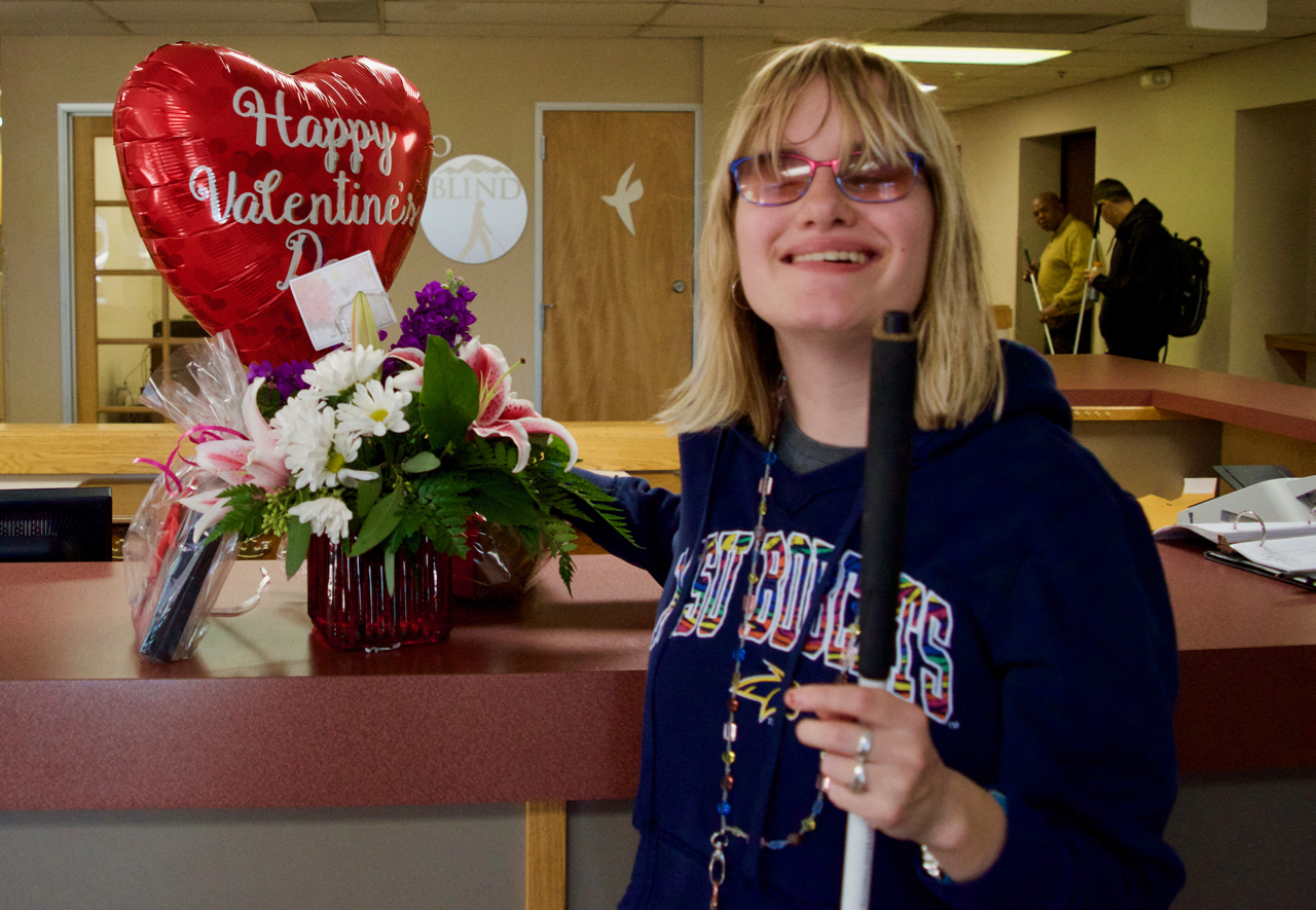 A smiling young woman holds a Happy Valentines Day Heart Shaped Balloon and Flower Arrangement