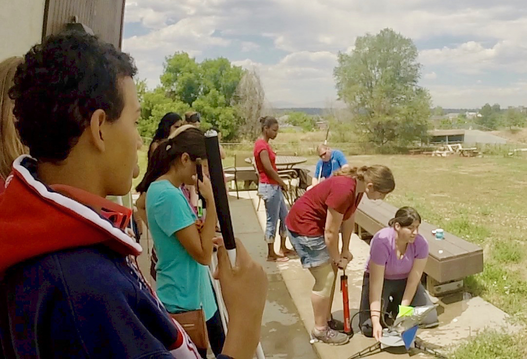 Jamie (bottom right) holding the rocket with a group of CCB youth launching water rockets