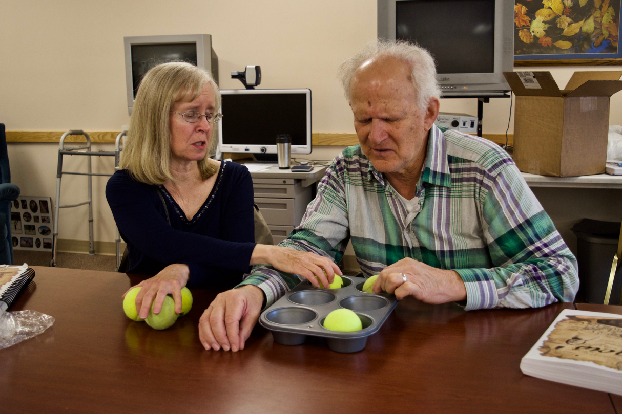 Steve works with Janet to learn the Braille Alphabet using a muffin tin and tennis balls