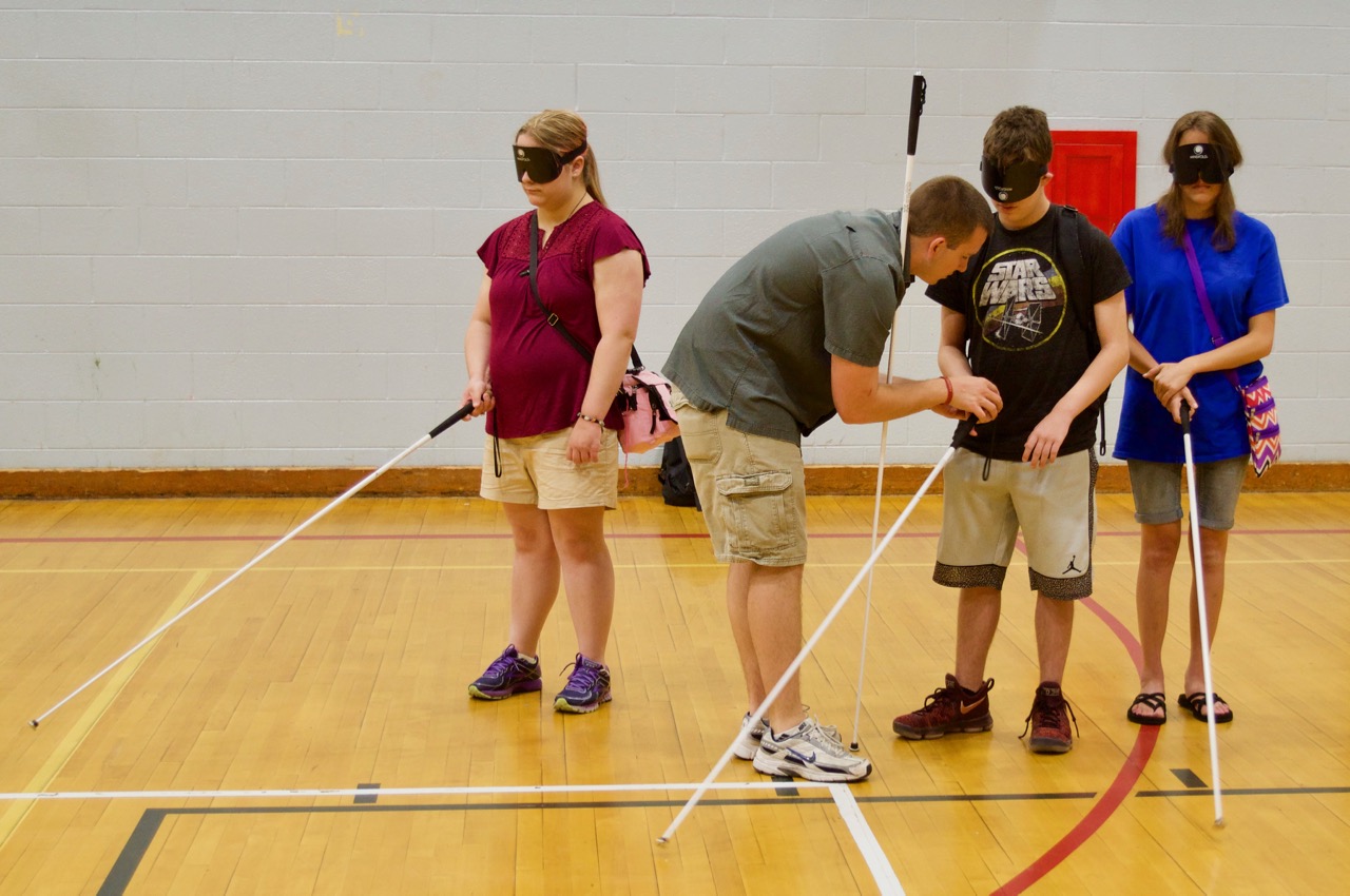 Garret works with 3 summer students in the Gym on holding their canes properly