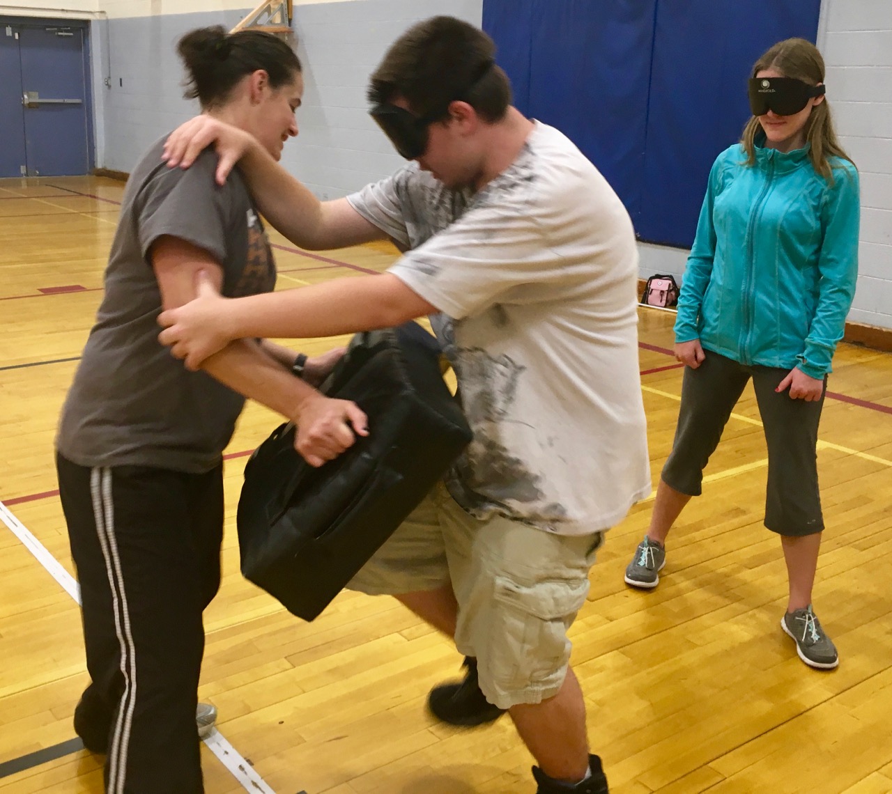 Masson learns how to put power in forward knee strikes while Rachael holds the pad. Maggie waits her turn to give it a try