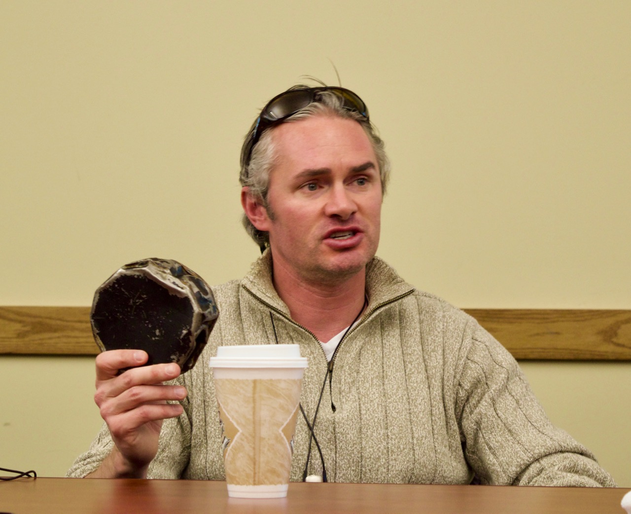 Craig Fitzpatrick holds up an adapted hockey puck while he gives a talk about Blind Hockey at the Colorado Center for the Blind