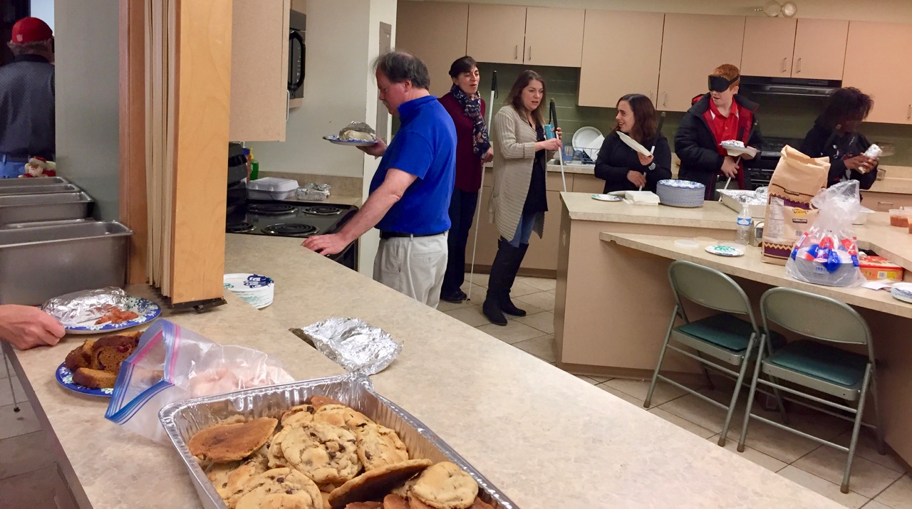 A line of people snakes its way through the large kitchen as people fill their plates with goodies