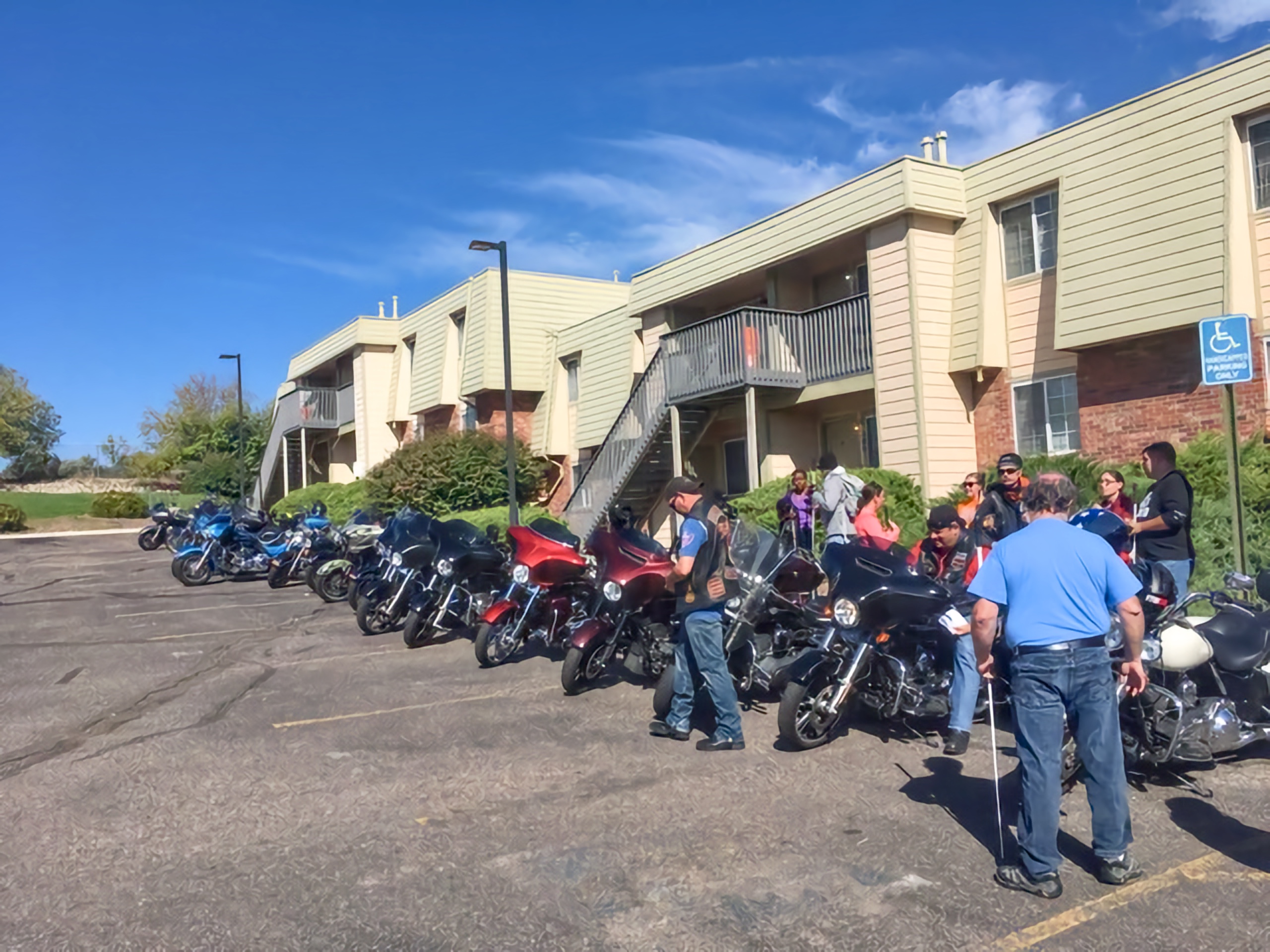 Students and staff near motorcycles lined up in front of McGeorge Mountain Terrace Apartments
