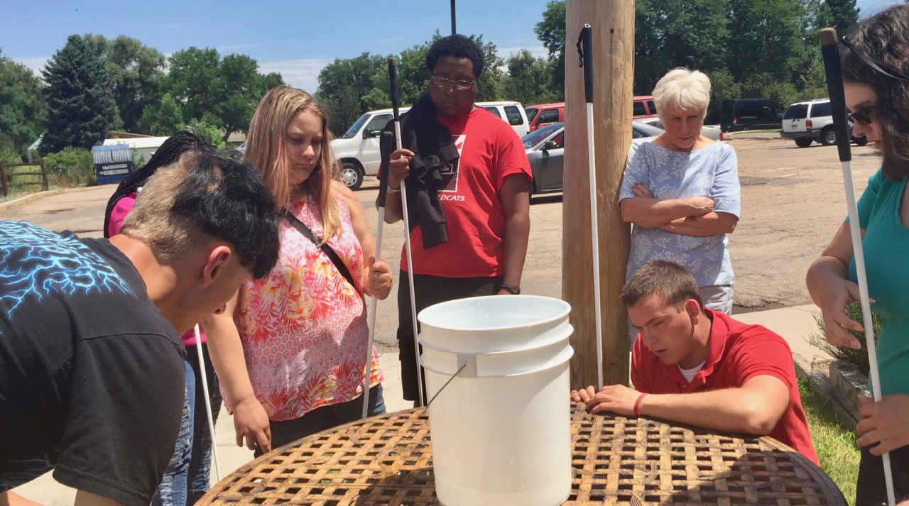 Ashley simulates how a tornado looks using a bucket and water, with Roland, Faye and Keishawn. Our volunteer Kay looks on.