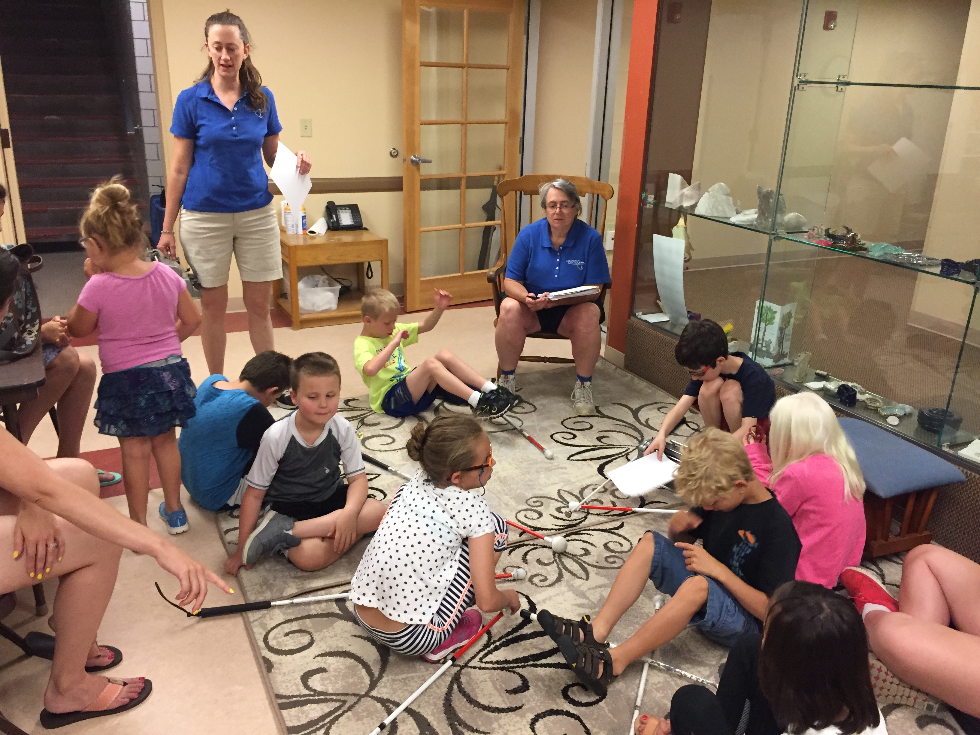 A teacher addresses students seated in a circle around her.