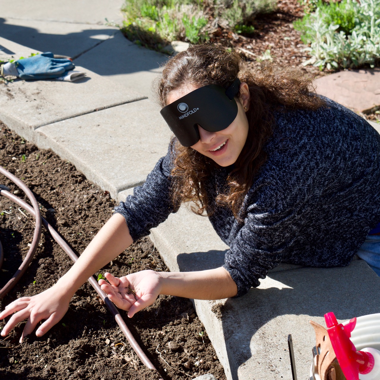 Ceci poking a hole with one finger and a hand full of tiny seeds in the other hand