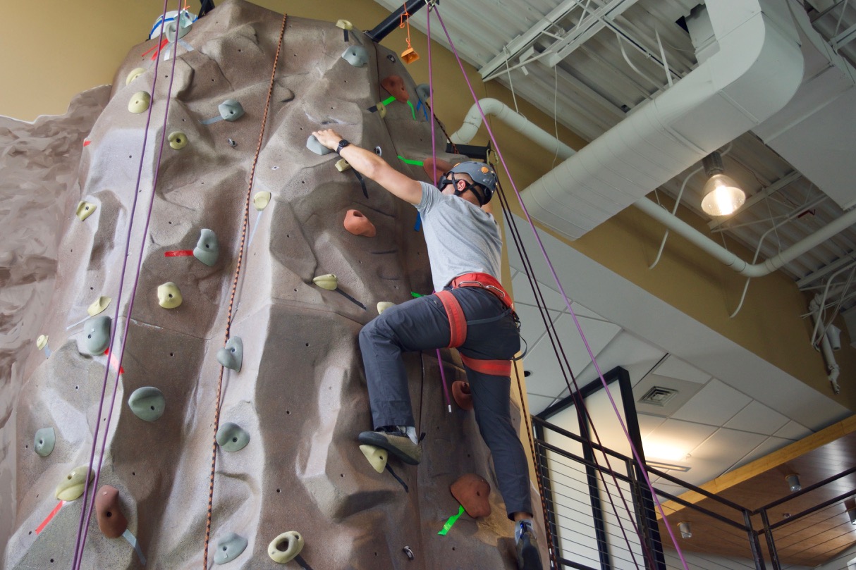 Cezar reaching for a hold as he nears the top of the climing wall