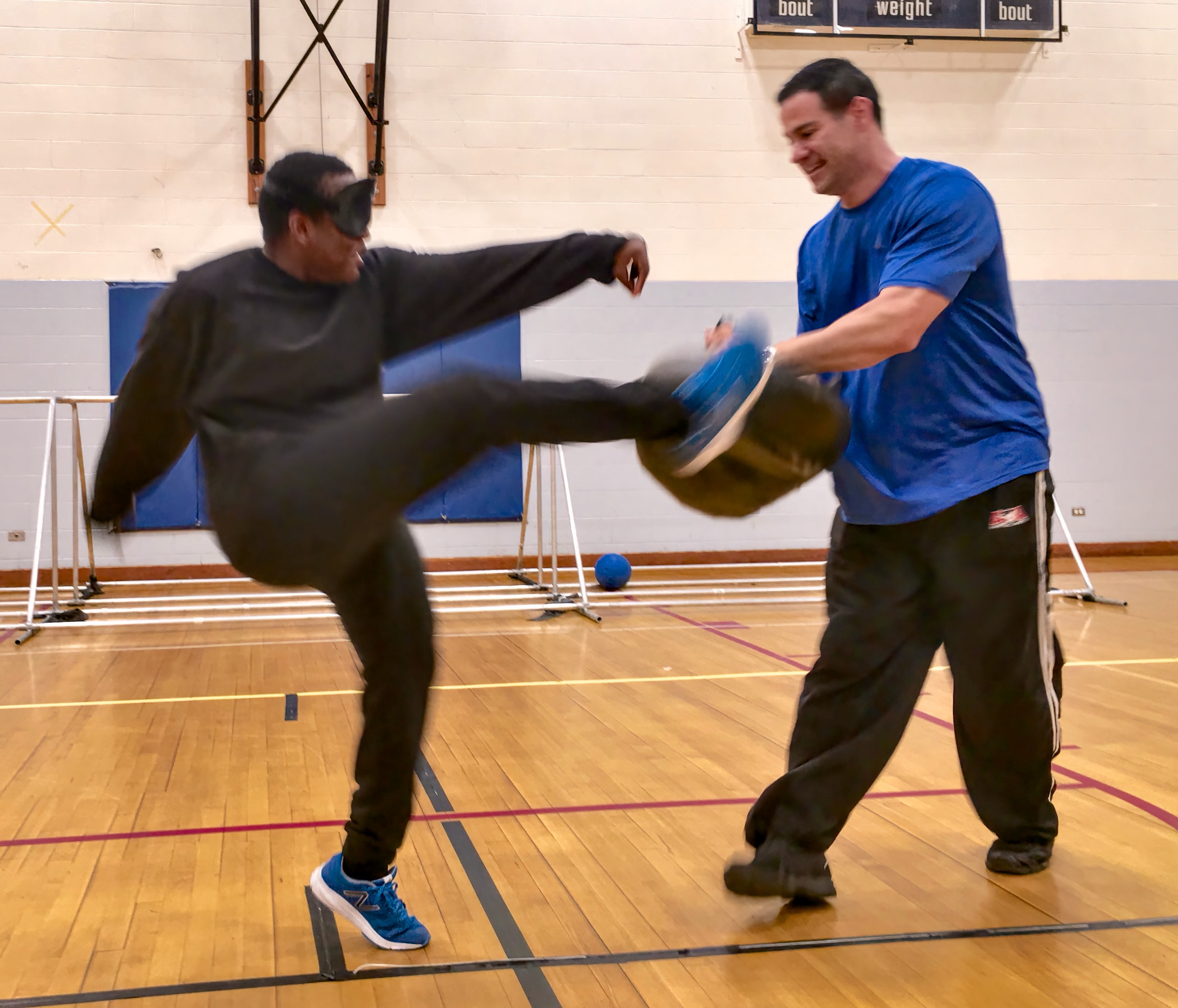 Student makes a High kick into a pad held by his instructor