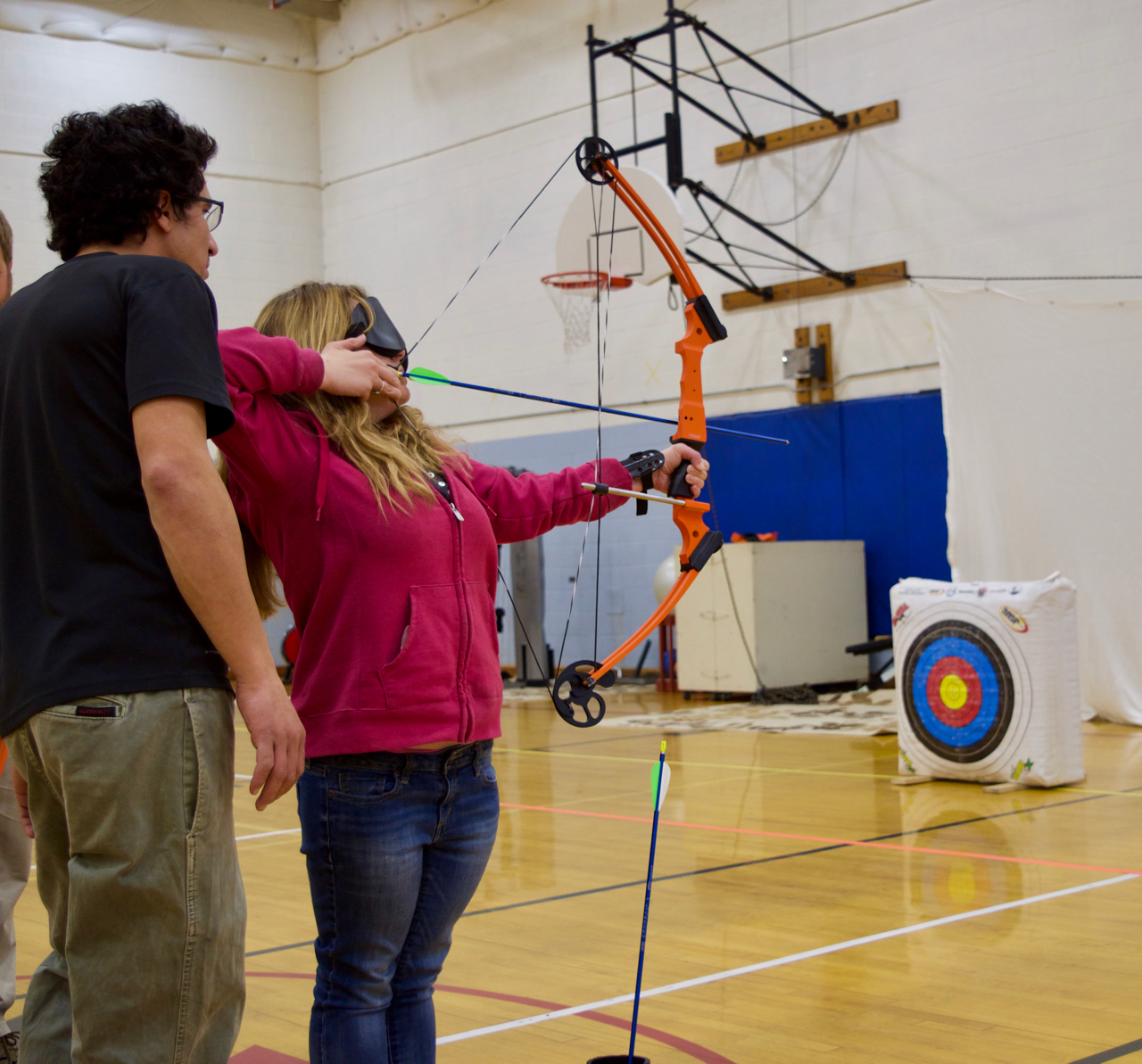 Courtney in sleepshades holding bow gets tips from NSCD's Mike