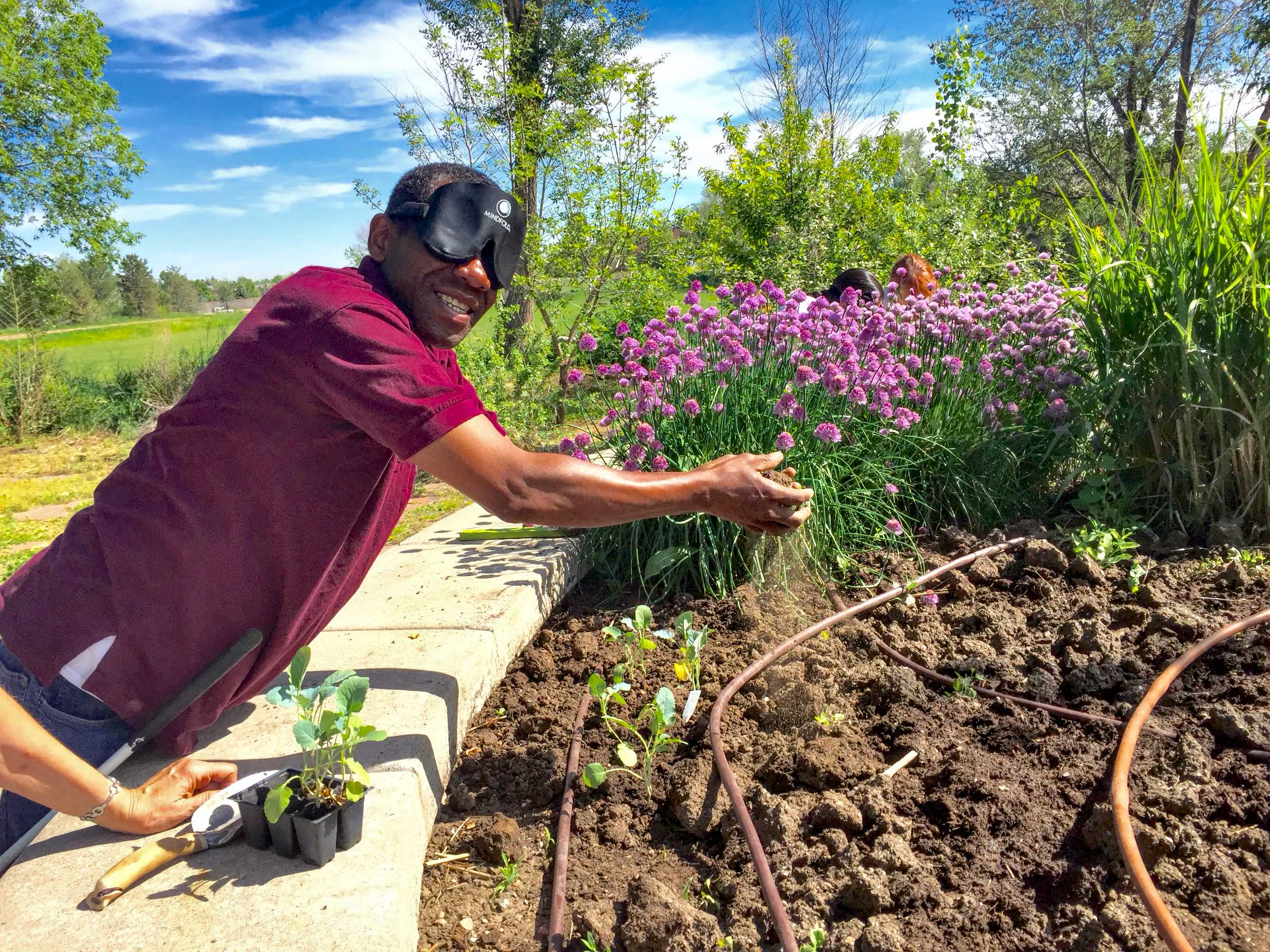 Man wearing sleepshades breaks clods of soil between his hands