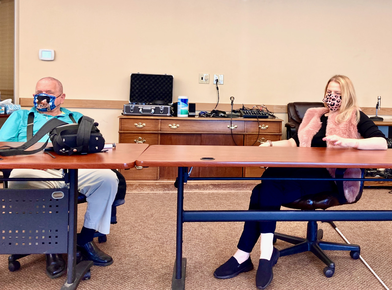 a man and woman wearing masks sit at nearby tables