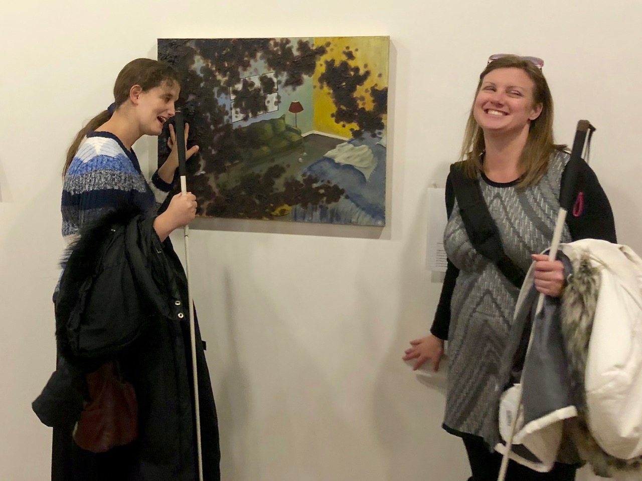 Jen looks at a tactile painting while Stefanie reads the Braille description