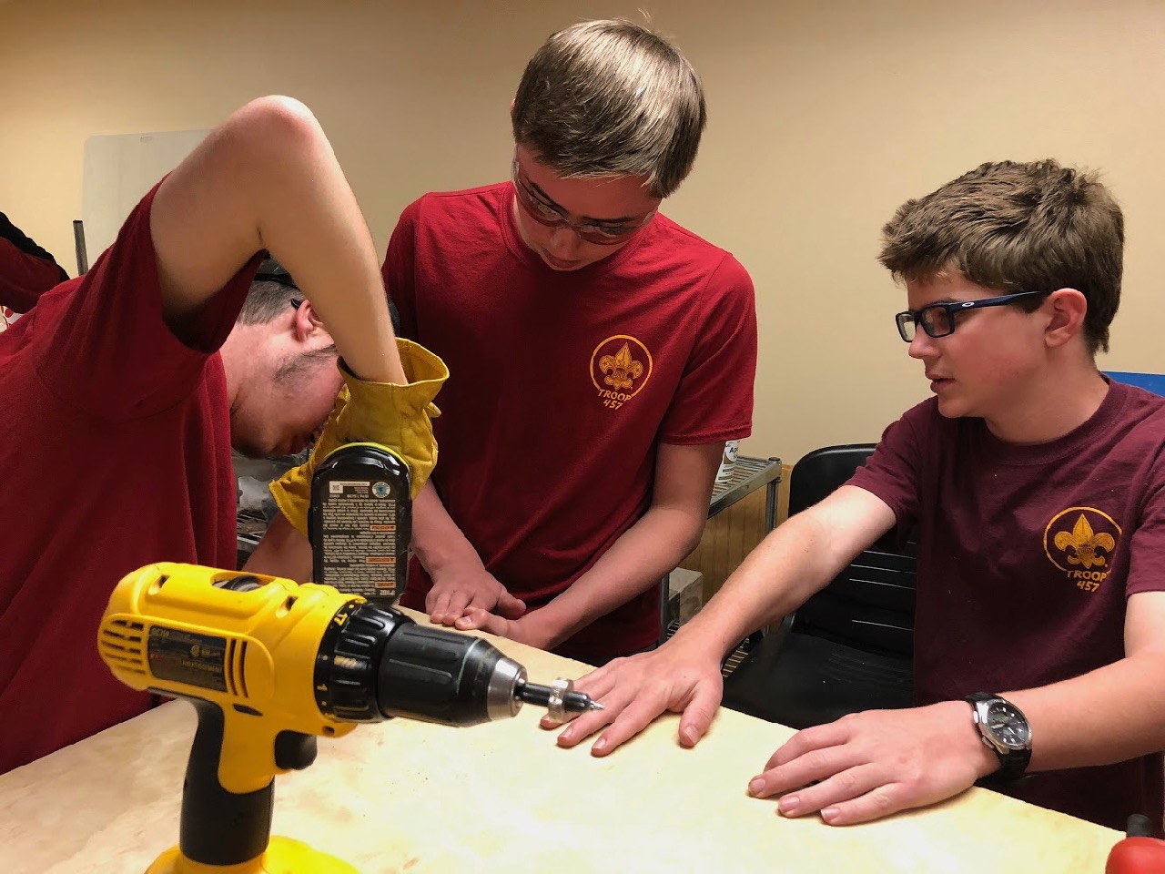Jonathan uses a drill to secure the bench top while Stephen and Lucas hold everything in place