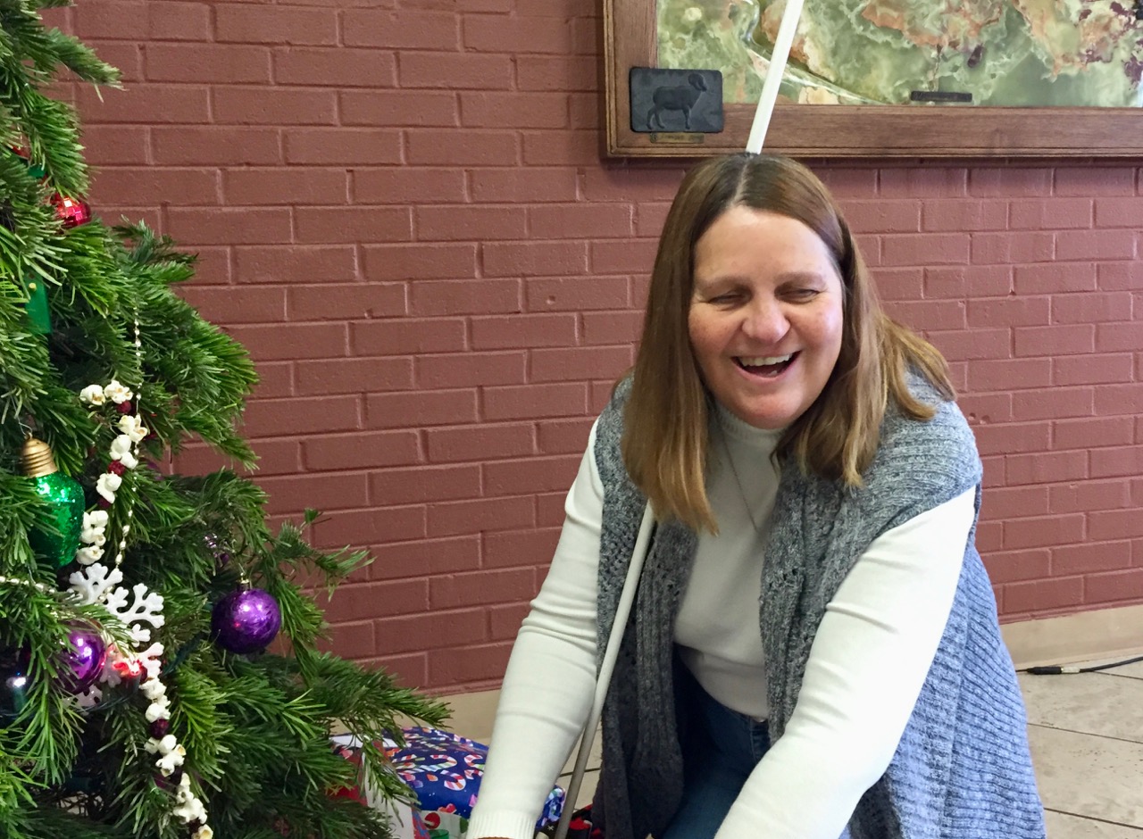 ulie reaches down under the Christmas Tree to retrieve a gift