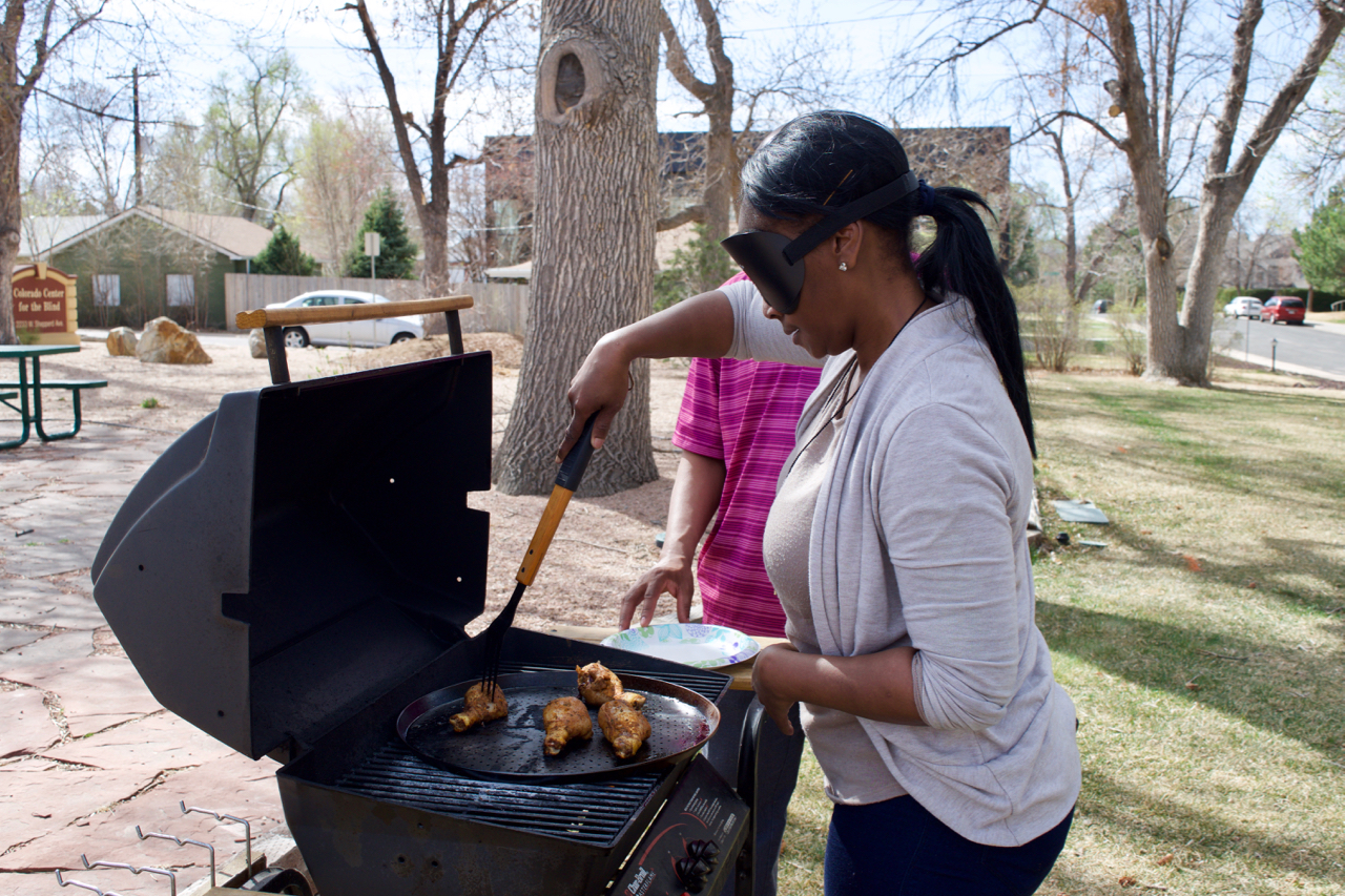 Laura in sleepshades tends chicken on the grill