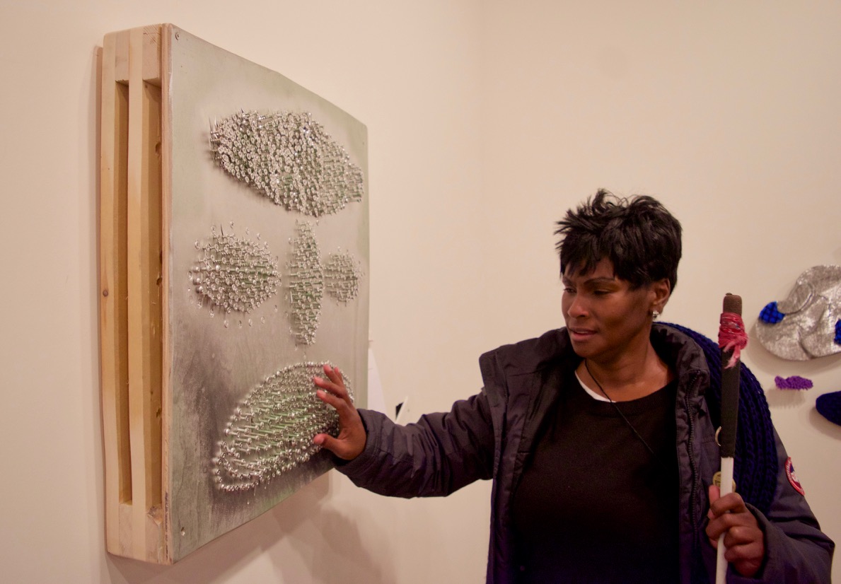 Laura looks at a piece made with various screws