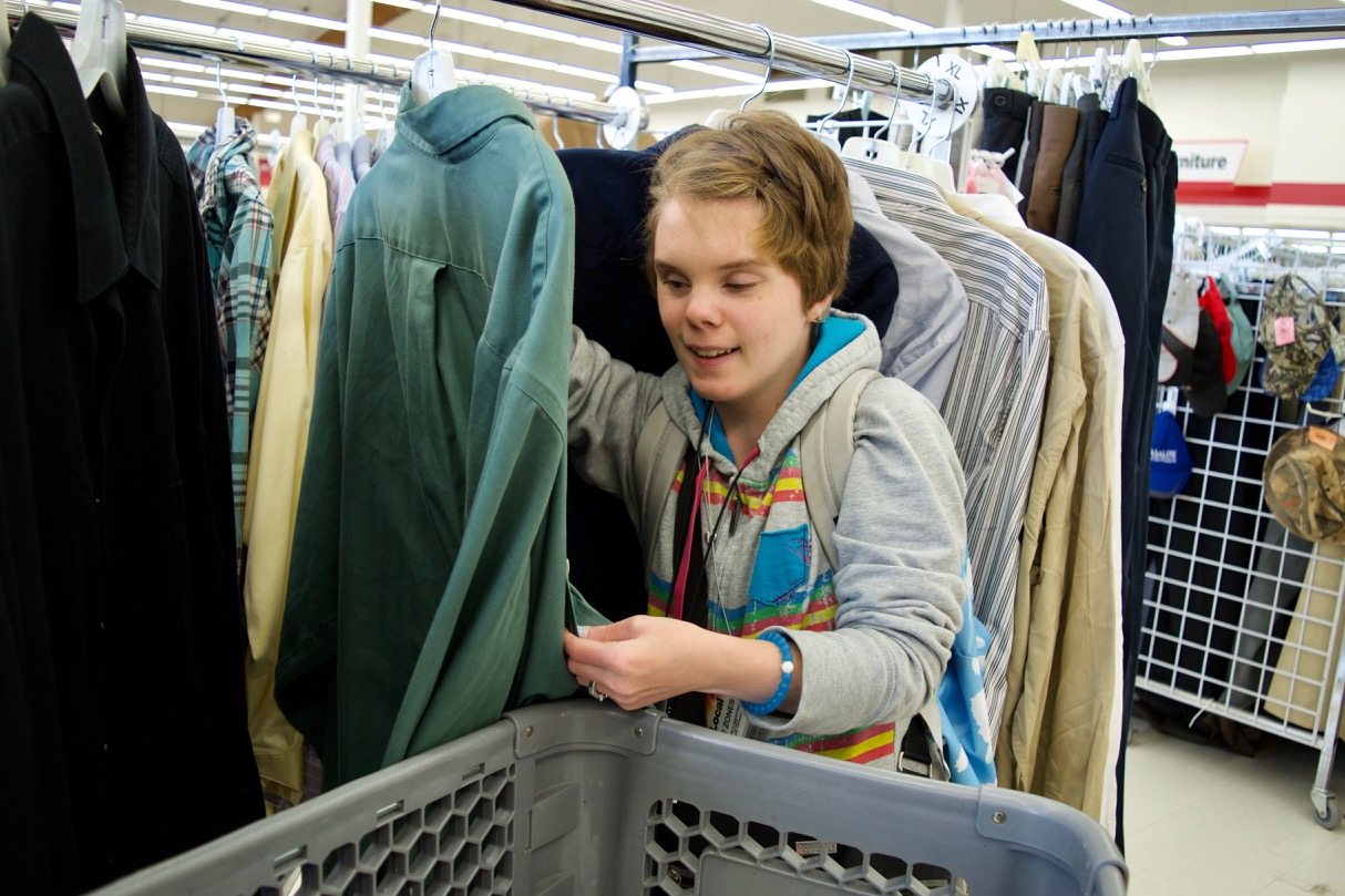 Layla works with a rack of shirts making sure all buttons are fastened and all of them have tags at the Arc Thrift Store