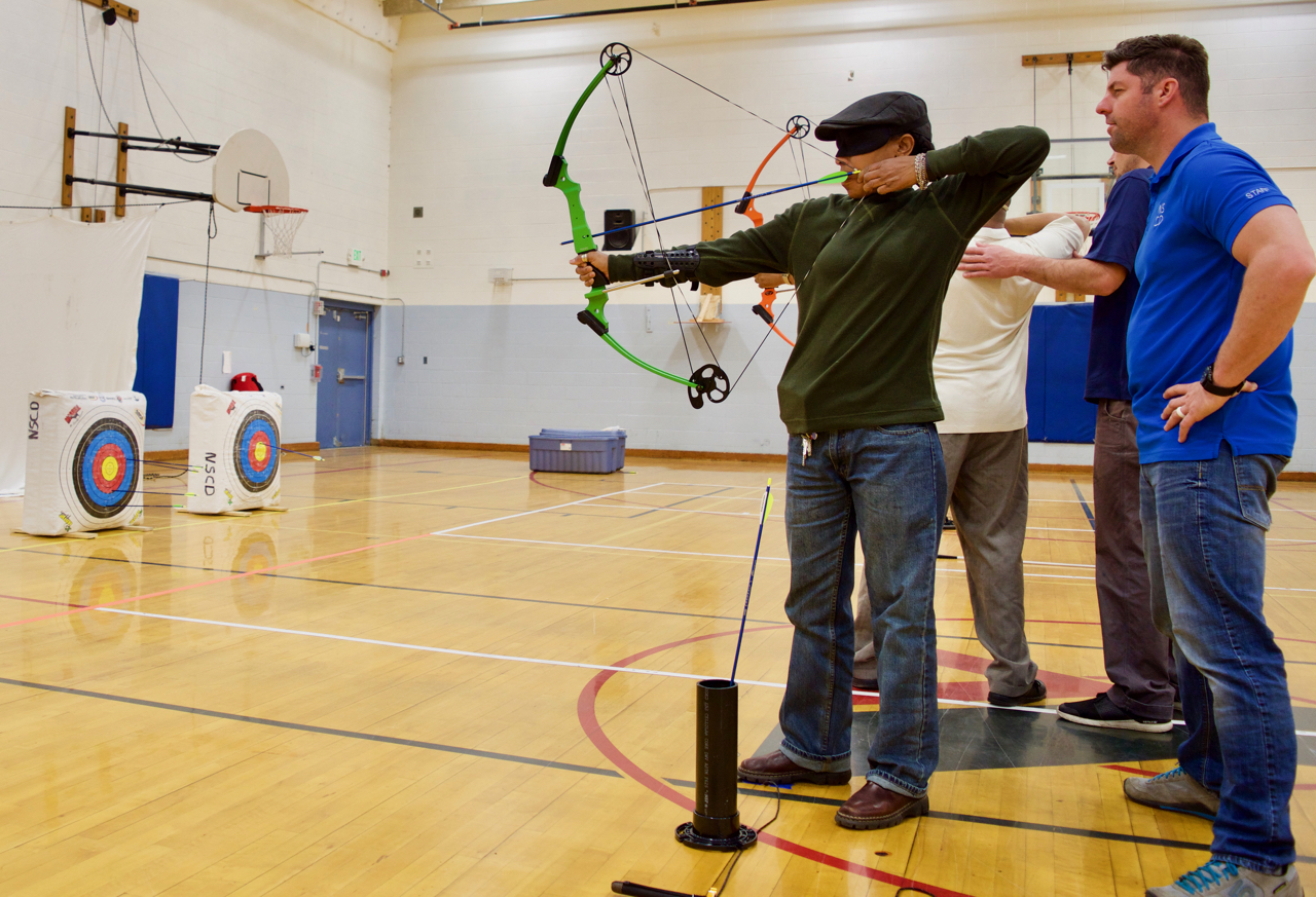 Lyne takes aim with her bow in Archery Class