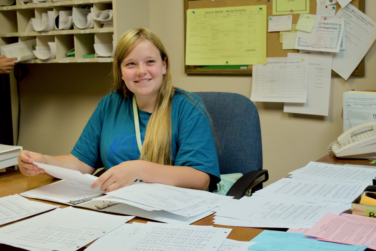 Maddy sorts through stacks of paperwork at Trinity Lutheran Church