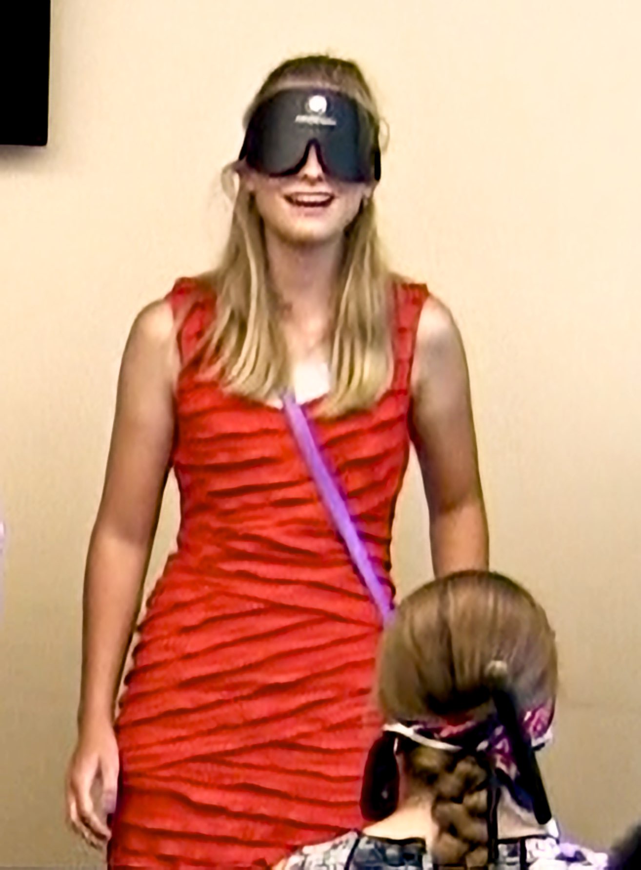 A smiling young woman wearing sleepshades